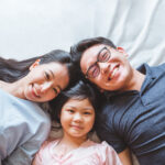 Happy Asian family laying on bed in bedroom with happy and smile, top view